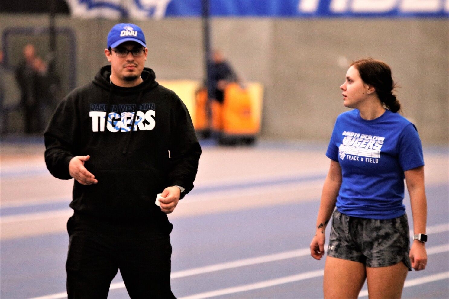 Dakota Wesleyan University Track and Field and Cross Country Head Coach Matthew Rosado coaching a female track athlete at an indoor track meet